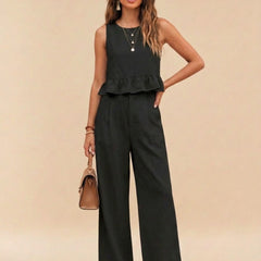 Woman wearing black peplum top and wide-leg trouser co-ord set