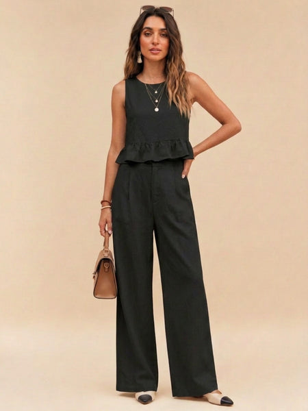 Woman wearing black peplum top and wide-leg trouser co-ord set